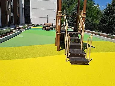A playground with a yellow surface and a green top.